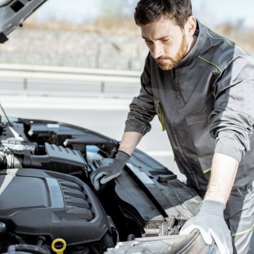 Auto mechanic repairing car outdoors